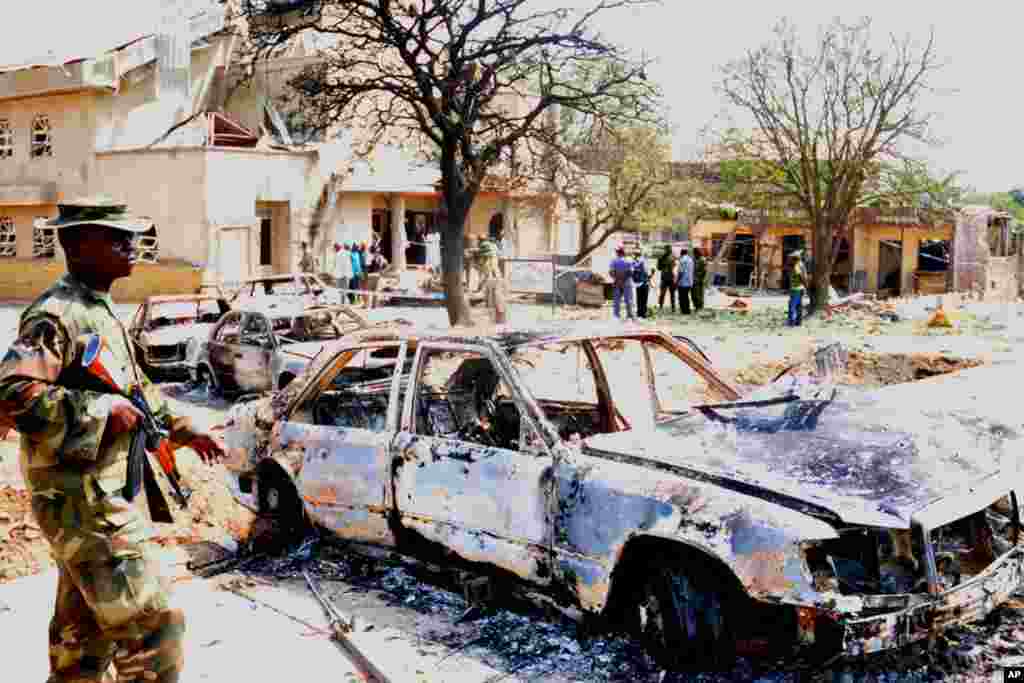 An armed soldier walks past a car destroyed in a Chritsmas day bombinb in Madalla, Nigeria. (AP)