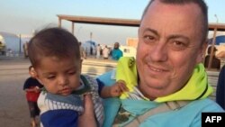 Trong bức ảnh do Văn phòng Đối ngoại và Khối thịnh vượng chung của Anh cung cấp, nhân viên cứu trợ người Anh Alan Henning đang bế một em bé ở trại tỵ nạn tại biên giới Thổ Nhĩ Kỳ và Syria. 