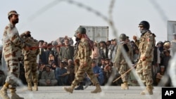 FILE - People wait to cross into Afghanistan at Pakistan's Chaman border post, Sept. 1, 2016. Afghanistan opposes a new Pakistani flag ceremony at the key border crossing between the countries.