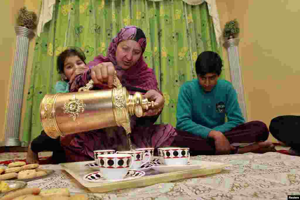 ایک خاتون پیالی میں چائے ڈال رہی ہے۔