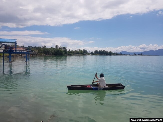 Seorang warga Kecamatan Nainggolan, Pulau Samosir tengah mengayuh sampan di Danau Toba, Sumatera Utara. (Foto: VOA/Anugerah Adriansyah)