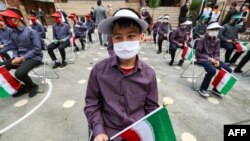 Para siswa mengenakan masker sambil menjaga jarak aman di sekiolah Nojavan, Teheran di tengah pandemi Covid-19 di Iran. 