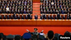 FILE - A conductor leads an orchestra as delegates stand for the national anthem during the closing session of the 19th National Congress of the Communist Party of China at the Great Hall of the People in Beijing, Oct. 24, 2017.