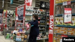 在南非約翰內斯堡南部購物中心的冠狀病毒病傳播期間，一名戴著口罩的購物者正在等待輪到她為她的雜貨付款 （路透社照片）