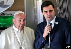 Pope Francis is flanked by Vatican spokesman Alessandro Gisotti, right, talking to journalists, during the flight from Rome to Panama City, Jan. 23, 2019.