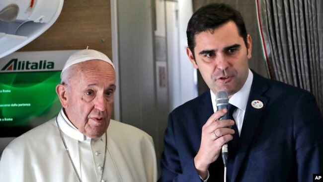 Pope Francis is flanked by Vatican spokesman Alessandro Gisotti, right, talking to journalists, during the flight from Rome to Panama City, Jan. 23, 2019.