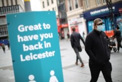 A man wearing a protective mask walks past a sign, amid the coronavirus disease (COVID-19) outbreak, in Leicester, Britain, June 29, 2020. REUTERS/Carl Recine