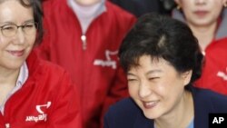 Park Geun-hye, right, then-interim leader of the ruling Saenuri Party, watches a television report on an exit poll of parliamentary elections, Seoul, April 11, 2012.