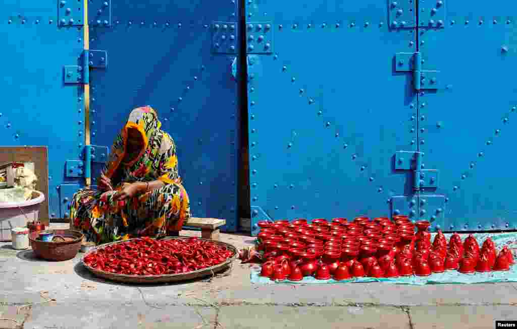 A woman paints earthen lamps which are used to decorate temples and homes during Diwali, the Hindu festival of lights, in Kolkata.