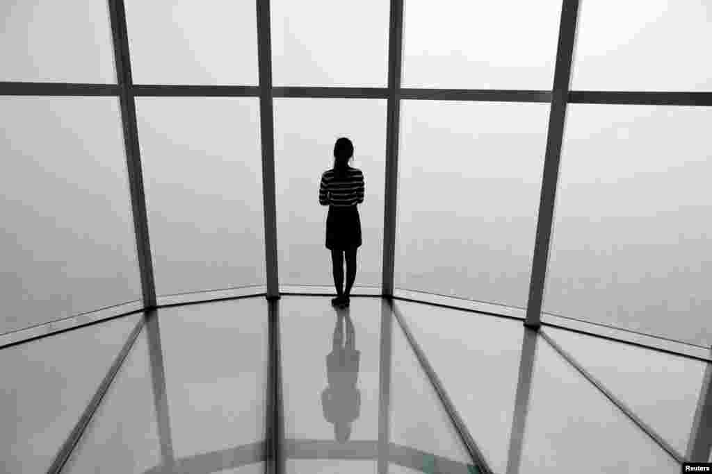 A woman looks at a view of Seoul shrouded by fine dust during a polluted day in Seoul, South Korea.