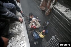 Civil defense help an unconscious woman from a shelter in the besieged town of Douma in eastern Ghouta in Damascus, Syria, Feb. 22, 2018.