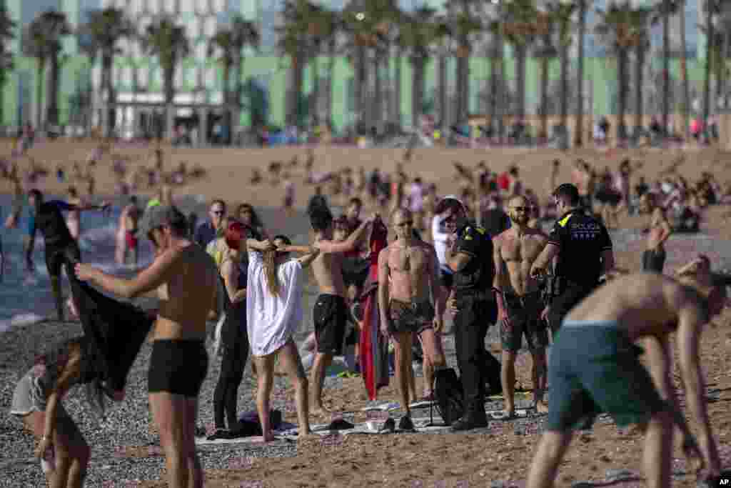 Police officers ask people to not sit at the beach in Barcelona, Spain as sunbathing and recreational swimming are still not allowed.