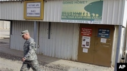 A U.S. Army soldier walks under a post office sign at Camp Victory near Baghdad, Iraq, October 15, 2011.