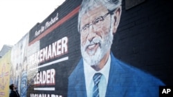 A man adds the finishing touch to a newly painted mural of Gerry Adams on the Falls Road, West Belfast, Northern Ireland, May, 2 2014.