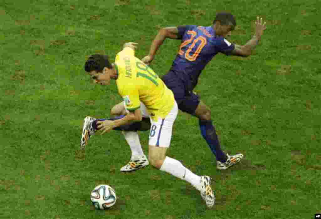 Brazil's Hernanes and Netherlands' Georginio Wijnaldum fight for the ball during the World Cup third-place soccer match between Brazil and the Netherlands at the Estadio Nacional in Brasilia, Brazil, Saturday, July 12, 2014. (AP Photo/Themba Hadebe)