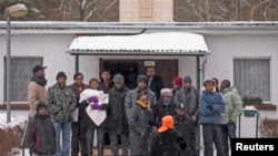 FILE - Asylum seekers stand outside an accommodation at a refugee holding center in the town of Bad Belzig some 135 km (84 miles) southwest of Berlin.