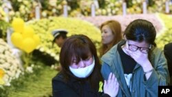 Relatives of a passenger aboard the sunken ferry Sewol weep as they pay tribute to the victims of the ship at a group memorial altar in Ansan, South Korea, May 4, 2014. 