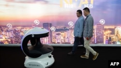 Visitors walk past an AI (Artificial Inteligence) security robot named APV3 with a facial recognition system at the 14th China International Exhibition on Public Safety and Security at the China International Exhibition Center in Beijing 