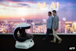 Pengunjung berjalan melewati robot keamanan AI (Artificial Inteligence) bernama APV3 dengan sistem pengenalan wajah di China International Exhibition on Public Safety and Security ke-14 di China International Exhibition Center di Beijing pada 24 Oktober 2018. (Foto: AFP)