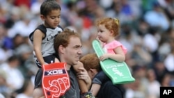 Fans watch during Father-Daughter Day in the seventh inning of a baseball game between the Chicago White Sox and the Texas Rangers, June 20, 2015, in Chicago.