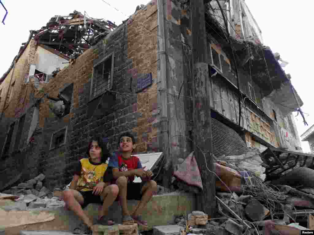 Children sit along a damaged street filled with debris in the besieged area of Homs, Sept. 19, 2013.