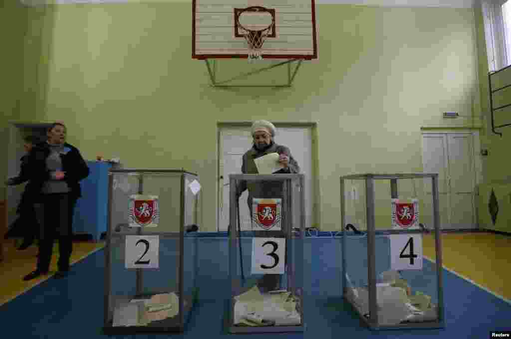 Seorang perempuan memberikan suaranya dalam referendum di tempat pemungutan suara di Simferopol, Krimea, Ukraina, 16 Maret 2014. 