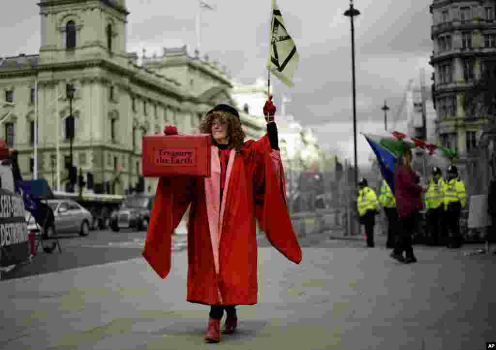 A woman dressed as the Speaker of the House of Commons holds a case with a message &#39;treasure the earth&#39; as she participates in a demonstration on the budget outside Parliament in London.