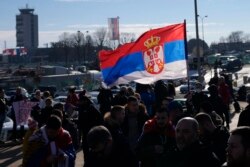 Fans wave a Serbian flag as Serbian tennis star Novak Djokovic arrives at Nikola Tesla Airport in Belgrade, Serbia, Jan. 17, 2022.