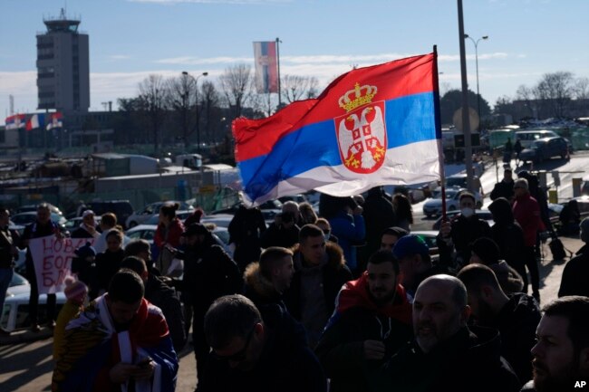 Para penggemar Novak Djokovic mengibarkan bendera nasional Serbia saat menunggu kedatangannya di bandara Beograd (17/1).