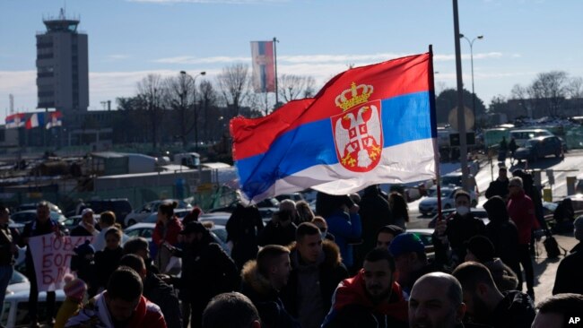 Fans wave a Serbian flag as Serbian tennis star Novak Djokovic arrives at Nikola Tesla airport in Belgrade, Serbia, Jan. 17, 2022.