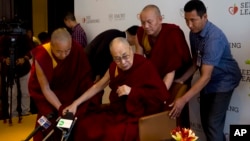 FILE - Tibetan spiritual leader, the Dalai Lama, center, is assisted by his aides as he arrives to interact with an audience of educators, in New Delhi, India, April 4, 2019.