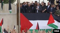 Presiden Palestina Mahmoud Abbas (atas tengah) melambaikan tangan setibanya di lokasi pemerintahan di Ramallah, Tepi Barat hari MInggu (25/9) dan dielu-elukan sebagai pahlawan.