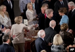 El presidente Trump saluda a su ex rival Hillary Clinton durante el banquete en el Congreso.