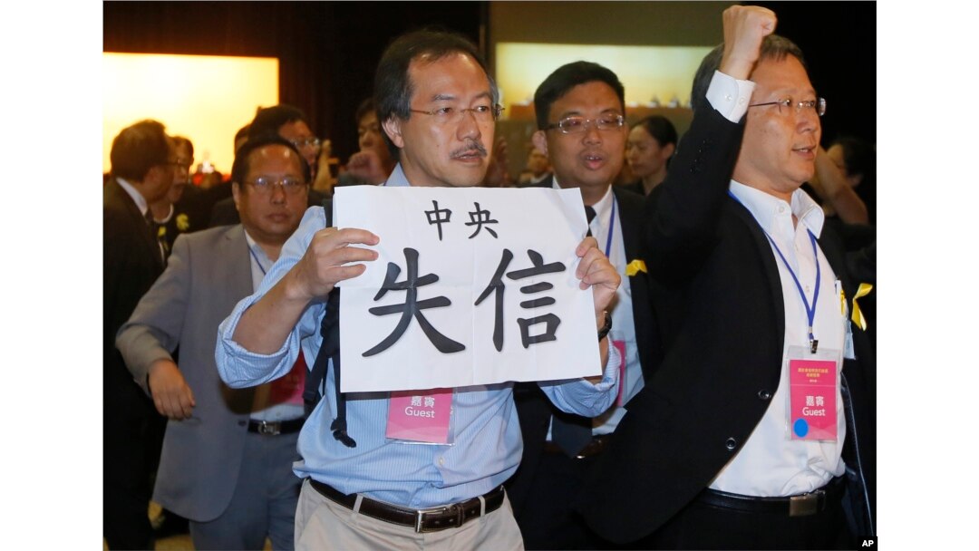 FILE - Pro-democracy lawmaker Fernando Cheung holds a placard which reads " Central Government break the promise " as he protests against Li Fei, deputy secretary general of the National People’s Congress Standing Committee, during a briefing session in Hong Kong.