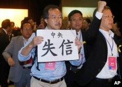 FILE - Pro-democracy lawmaker Fernando Cheung holds a placard which reads " Central Government break the promise " as he protests against Li Fei, deputy secretary general of the National People’s Congress Standing Committee, during a briefing session in Hong Kong.