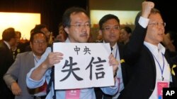 FILE - Pro-democracy lawmaker Fernando Cheung holds a placard which reads " Central Government break the promise " as he protests against the deputy secretary general of the National People’s Congress Standing Committee, during a session in Hong Kong, Sept. 1, 2014.