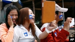 A supporter, center, of the newly merged Cambodia National Rescue Party, holds an iPad during an election campaign on the outskirts of Phnom Penh, Jul. 3, 2013.