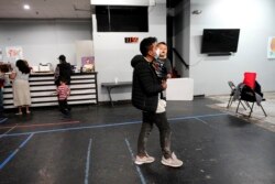 Misael Cuyuch, 23, a migrant from Guatemala, walks with his son, Rodrigo Cuyuch, 1, inside a respite center after they were taken into custody and released from U.S. Customs and Border Protection while trying to sneak into the U.S., Friday, March 19, 2021