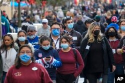 Visitors wearing face masks walk down Main Street USA at Disneyland in Anaheim, Calif., Dec. 27, 2021.