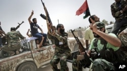 Libyan rebel fighters shoot in the air and shout religious slogans as they attend the funeral of 7 fallen comrades killed the day before during the battle for the control of the oil rich town of Brega at the main cemetery in the Libyan rebels stronghold c