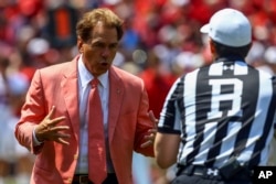 Alabama football coach Nick Saban talks with a referee during the first half of an NCAA spring game, April 21, 2018, in Tuscaloosa, Alabama. The Crimson Tide are the defending national champions.