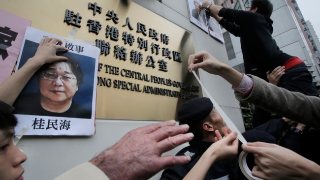 香港抗议者在北京驻香港机构中联办前贴上铜锣湾书店失踪老板桂民海的照片。 （2016年1月3日）