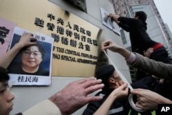 FILE - Protesters try to stick photos of missing booksellers, one of which shows Gui Minhai (L), during a protest outside the Liaison of the Central People's Government in Hong Kong, Jan. 3, 2016.