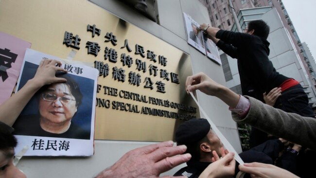 香港抗议者在北京驻香港机构中联办前贴上铜锣湾书店失踪老板 桂民海 的照片。 (2016年1月3日)