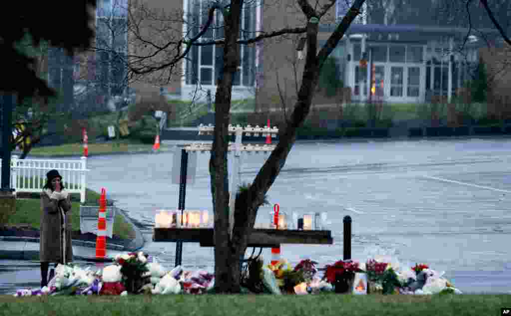 Une femme priant devant&nbsp; un m&eacute;morial improvis&eacute; &agrave; l&#39;&eacute;glise catholique Sainte Rose de Lima&nbsp; de Newtown 