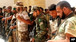 Newly-arrived Iraqi Shi’ite militiamen check their weapons in the predominately Sunni city of Nukhayb, southwest Iraq, May 21, 2015.