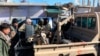 This photo provided by the Kurdish-led Syrian Democratic Forces shows fighters from the Kurdish-led Syrian Democratic Forces gathered around a body of an Islamic State group gunman who was killed after an attack on Gweiran Prison, in Hasakah, northeast Syria, Jan. 21, 2022.