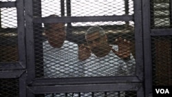 Al-Jazeera English bureau chief Mohammed Fahmy, right, and correspondent Peter Greste, in a defendant's cage during courtroom appearance, Cairo, April 22, 2014. (Hamada Elrasam for VOA)