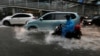 People ride motorcycles through a flooded street in a business district in Jakarta, Indonesia, Dec. 11, 2017. 