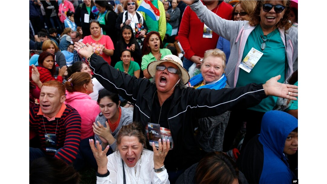 Inocencia Polanco, of Philadelphia and originally form the Dominican Republic, center in hat, joined by Freddy Espana of Honduras, left in striped shirt, and Maria Zuleta of Columbia, low center in white, pray a novena together as they wait for Pope Fran